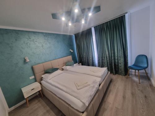 a bedroom with a bed and a blue chair at Unilux Residence in Beiuş