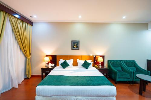 a hotel room with a bed and green chairs at واحد لواحد للشقق المخدومة -اقتصادي in Al Khobar