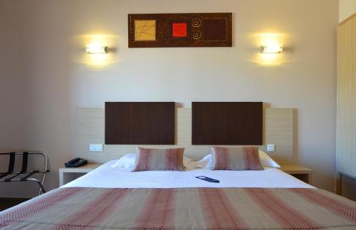 a bedroom with a large bed with two pillows at Hôtel A Madonetta in Bonifacio