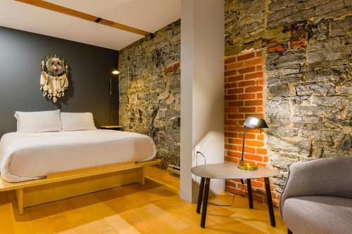 1 dormitorio con cama y pared de ladrillo en Les Lofts St-Paul - Par Les Lofts Vieux-Québec, en Quebec