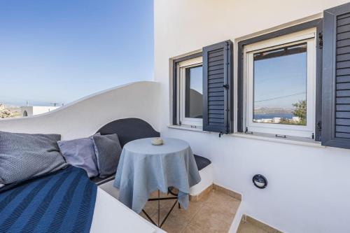 a living room with a table and two windows at Aelia Suites Akrotiri, Santorini in Akrotiri