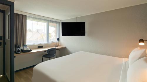 a hotel room with a bed and a desk and a window at Campanile NATURE - Meaux in Meaux