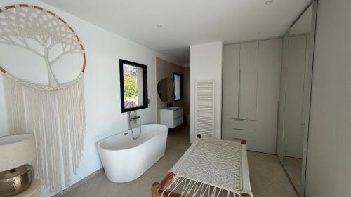 a bathroom with a large white tub and a mirror at villa la baies des anges in Calcatoggio