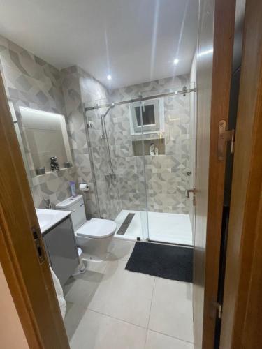 a bathroom with a shower and a toilet and a sink at Appartement suite in Cabo Negro