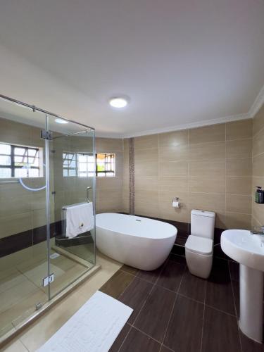 a bathroom with a tub and a toilet and a sink at Lusoi Gardens Naromoru in Nyeri