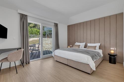 a bedroom with a bed and a desk and a balcony at Villa Prestige in Baška Voda