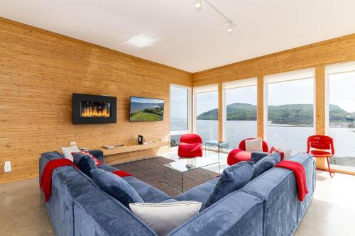a living room with a blue couch and red chairs at Hôtel à la maison - Panache, spa et fleuve in Baie-Saint-Paul