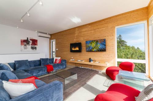 a living room with a blue couch and red chairs at Hôtel à la maison - Panache, spa et fleuve in Baie-Saint-Paul