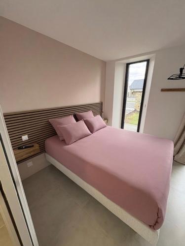 a bedroom with a large bed with pink pillows at Chambre d'hôtes Lilas in Saint-Lyphard