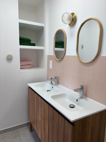 a bathroom with a sink and two mirrors at Chambre d'hôtes Lilas in Saint-Lyphard