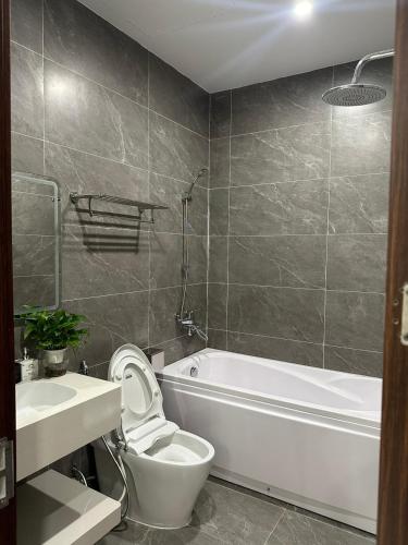 a bathroom with a white tub and a toilet and a sink at Sunny Hotel in Ðố Sơn