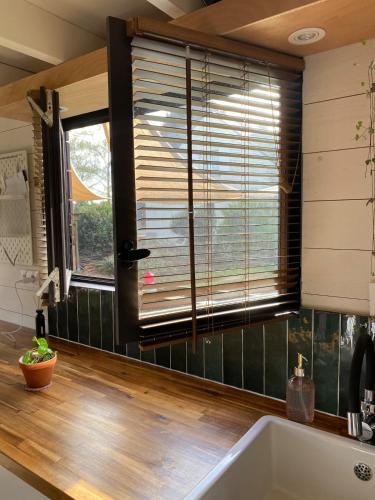 a kitchen with a tub and a window with blinds at Tiny House de Clara in Avrillé