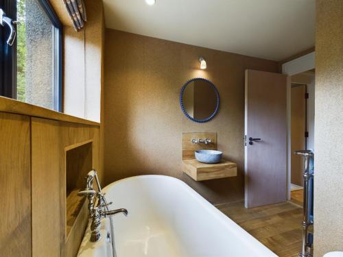 a bathroom with a tub and a sink and a mirror at Hygge House in Woodside