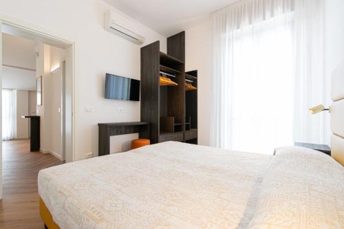 a white bedroom with a bed and a television at Residence Caterina in Cattolica
