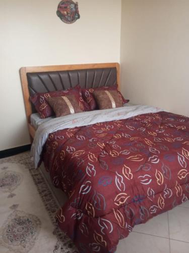 a bed with a red comforter and pillows on it at Mimi Home Stays in Voi