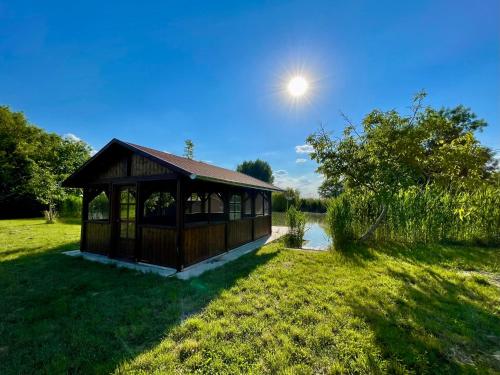 a small building in a field with the sun in the sky at Akácos Tanya Szarvas in Szarvas