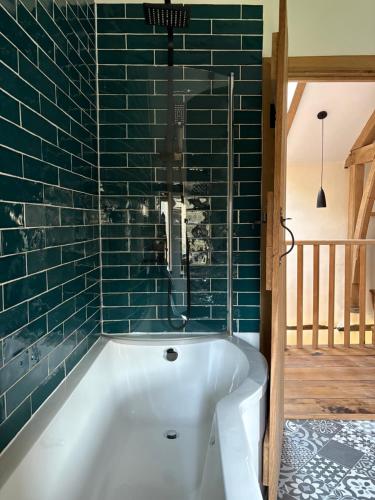 a bath tub in a bathroom with green tiles at Woolladon Hall in Meeth