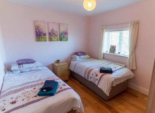 a bedroom with two beds and a window at Mariner's Rest - Cahersiveen in Cahersiveen
