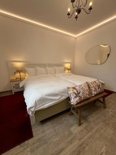 a bedroom with a large white bed and a bench at Penzion u Svatého Prokopa in Středokluky