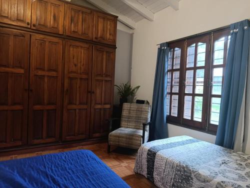 a bedroom with a bed and a chair and a window at Comfortable house in La Falda in La Falda