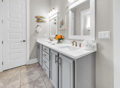 a white bathroom with a sink and a mirror at Beachful Bliss in Santa Rosa Beach
