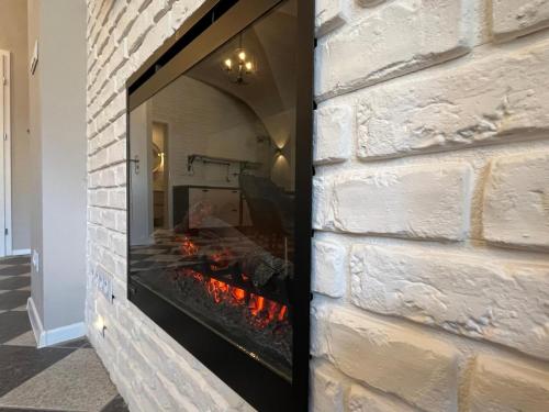a brick fireplace with a fire in it at Apartament Florian Rynek 3 in Radków