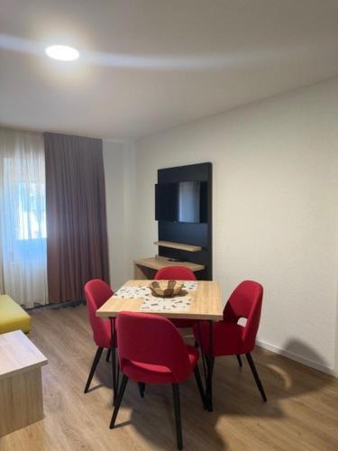 a dining room with a table and red chairs at Die Perle an der Wutach in Lauchringen