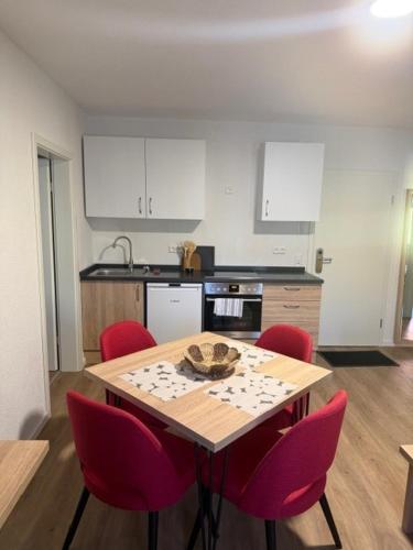 a kitchen with a wooden table with red chairs at Die Perle an der Wutach in Lauchringen
