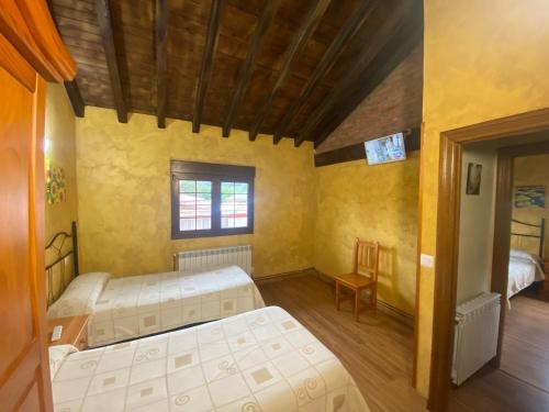 a room with two beds and a table and a chair at Los Avellanos Casa 1 in Celis