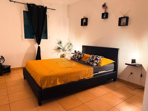 a bedroom with a bed with a yellow bedspread at L'ile au Paon in Les Abymes