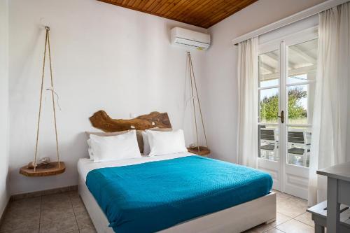 a bedroom with a bed with blue sheets and a window at Serenity Apartments, Next to the Beach in Agios Georgios
