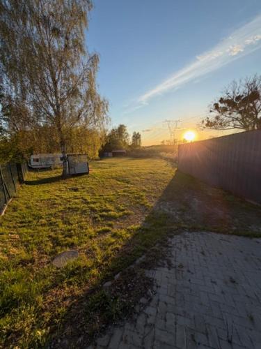 a field of grass with the sun setting in the background at Przystań Lubikowo in Lubikowo