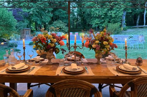 a wooden table with candles and flowers in vases at La Maison 1680 in Couches