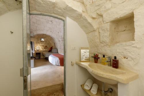 a bathroom with a stone wall and a bedroom at Puntebianche Resort in Ceglie Messapica