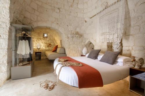 a bedroom with a large bed and a stone wall at Puntebianche Resort in Ceglie Messapica