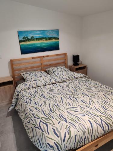 a bed in a bedroom with a painting on the wall at Espadrille Océan in Léon