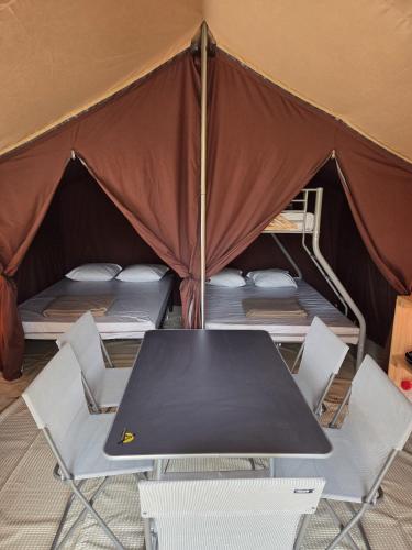 a table and chairs in a tent with beds at Camping de Mer - Onlycamp in Cucq
