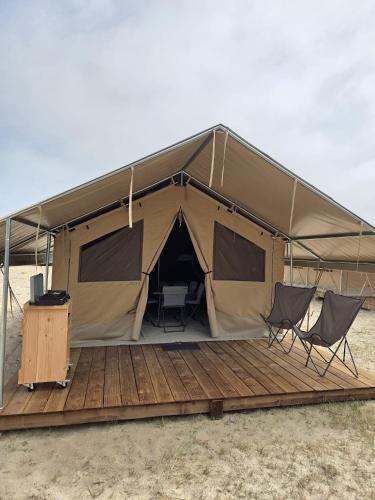 a tent in the desert with two chairs and a table at Camping de Mer - Onlycamp in Cucq