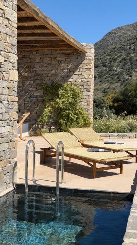 a pool with tables and benches next to a stone building at Egeo Paros in Kampos Paros