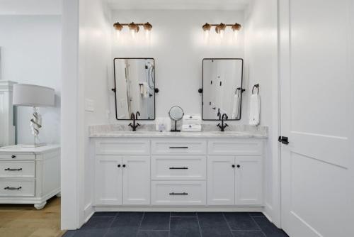a white bathroom with two sinks and two mirrors at The Perch in Gulf Shores