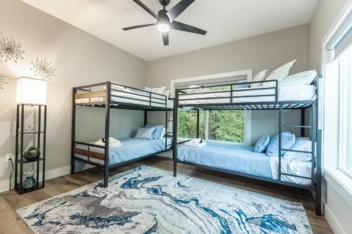 two bunk beds in a bedroom with a ceiling fan at Cliffside Modern Villa. Secluded and accessible. in Asheville