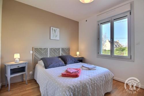 a bedroom with a bed with blue pillows and a window at Maison d'hôtes de kervor in Plouézec