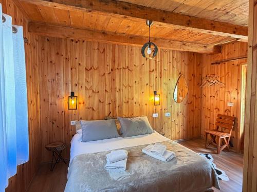 a bedroom with a bed in a wooden wall at Vila Shkalla in Theth