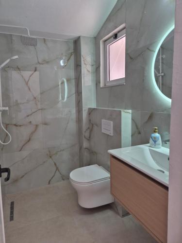 a bathroom with a toilet and a sink and a shower at Rooms and Apartments Analipsi in Shëngjin