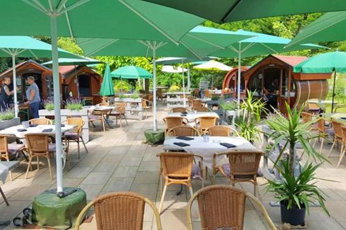 a patio with tables and chairs with green umbrellas at Hotel Restaurant Rodetal in Nörten-Hardenberg