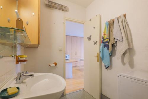 un bagno bianco con un lavandino e una porta di Chez Maïté a Vals-les-Bains