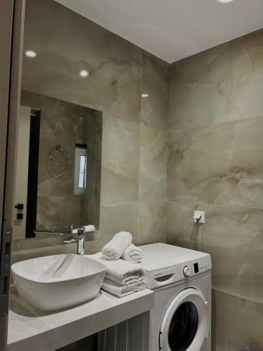a bathroom with a sink and a washing machine at Kostas apartaments in Korinthos