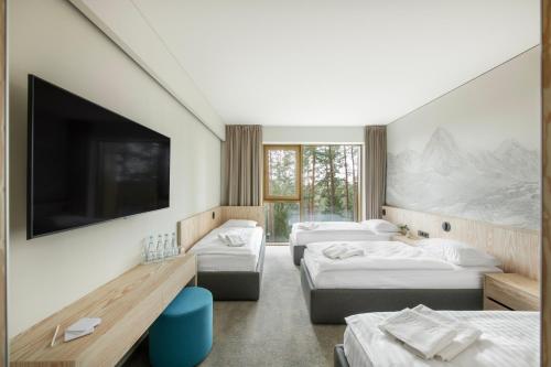 a hotel room with two beds and a flat screen tv at Snow Hotel Druskininkai in Druskininkai