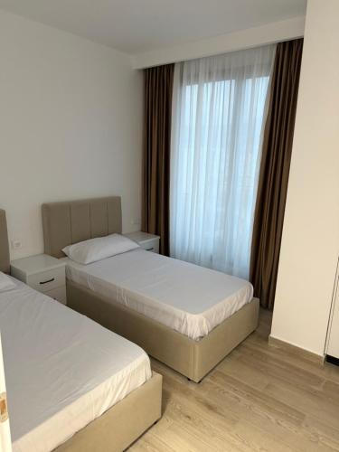 two beds in a hotel room with a window at Lunea Apartment Palm Residence in Vlorë