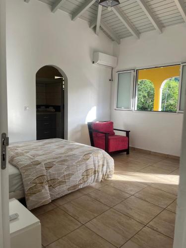 a bedroom with a bed and a red chair at Le coin des plaisir in Deshaies